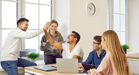 Good job. Well done. Team of happy positive cheerful joyful male and female university students and friends sitting at desk celebrating homework assignment project success. Education, teamwork concept