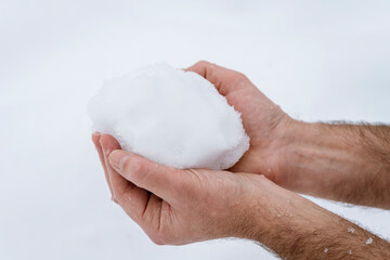 Clasped hands of a man holding frozen snow