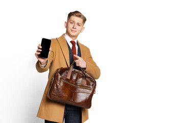 Portrait of young businessman, student, elegant man wearing suit and beige coat using phone...