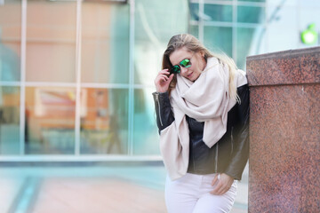Fototapeta premium young blond slavic woman with long hair in black leather jacket closeup street portrait with glasses on shaping mall background