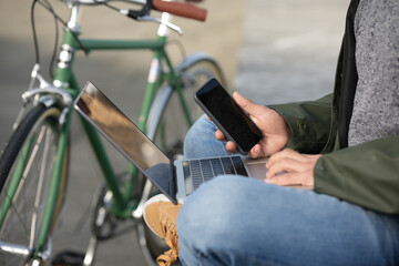 Obraz premium Closeup of man using phone and laptop beside classic bicycle