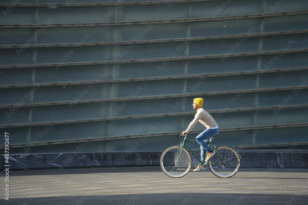 Wall mural Hispanic man riding an urban bicycle in the sun.