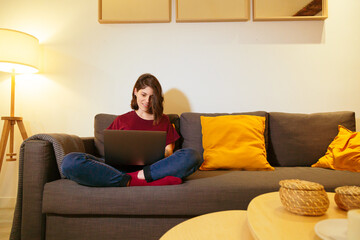 Obraz premium woman in an apartment relaxing on the sofa with a laptop