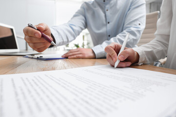 Businesspeople signing contract at table in office, closeup
