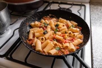 Cooking pasta with tomato sauce in pan