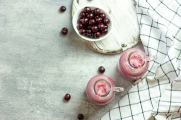 A bottle of cherry smoothies on a white background, cherries in bulk and in a plate. Morning summer breakfast