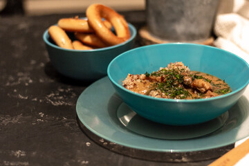 Buckwheat with meat and sauce in a blue plate, sprinkled with herbs. On a dark table. The concept of lunch, or a hearty dinner
