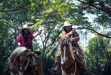 Cowboy.Group of cowboy riding horse and holding gun in his hand are ready for shooting.