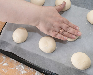 wooman hand press raw dough, round pieces. baking buns with cottage cheese.