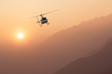 Fototapeta na wymiar helicopter in flight at sunset in the high mountains