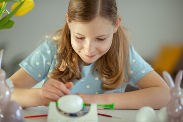 Pretty happy little girl painting eggs for easter celebtation