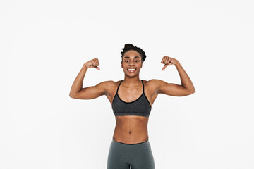 Young black sportswoman smiling and looking showing her biceps