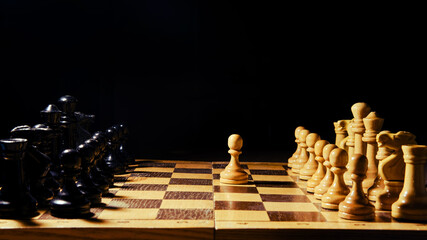 The opening of the chess game with the move of the white king pawn e2-e4, copy space on a black background
