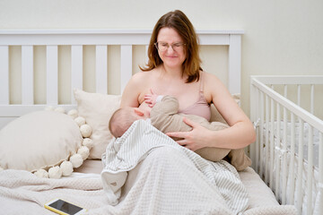 Pain and problems in a woman while breastfeeding a baby. Mother experiences discomfort while...