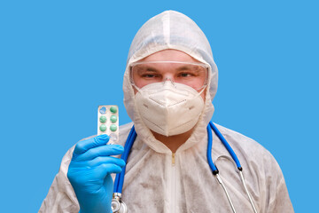 Man doctor medic in a protective suit uniform with goggles and face mask on a studio blue background. Paramedic in white antiviral protective clothing wearing an N95 respirator and safety glasses