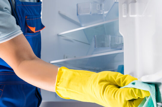 A Man From The Cleaning Service Washes Inside The Refrigerator To Disinfect It, Side View