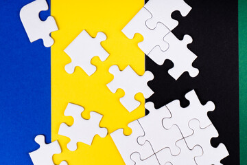 Missing jigsaw puzzle pieces. Business concept. Fragment of a folded white jigsaw puzzle and a pile of uncombed puzzle elements against the background of a colored surface.