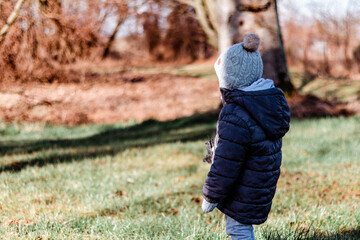 Chłopczyk wpatrujący się w parku na roślinność.