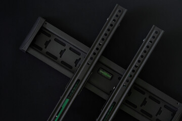 Modern metal bracket for wall mounting a TV or computer monitor on a black background. Diagonal