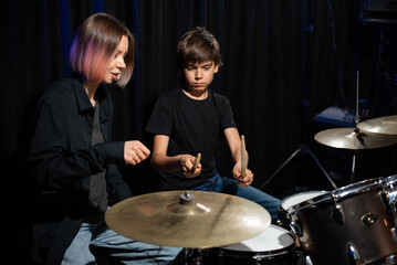 Fototapeta na wymiar Young woman teaching boy to play drums.