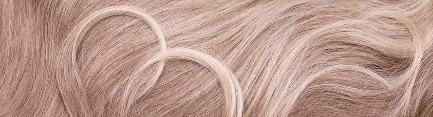 Background hair closeup. Female long blond hair close-up as a background. Beautifully laid wavy...