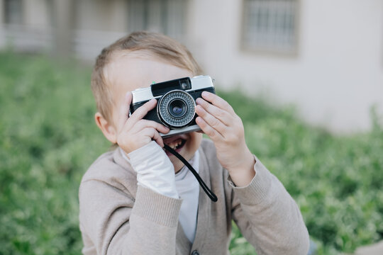 Little happy boy hold film analogue vintage retro photo camera