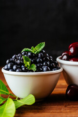 a variety of wild berries in a bowl on a wooden background. rasp