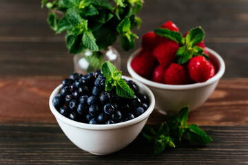 a variety of wild berries in a bowl on a wooden background. rasp