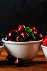 a variety of wild berries in a bowl on a wooden background. rasp