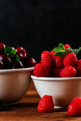a variety of wild berries in a bowl on a wooden background. rasp