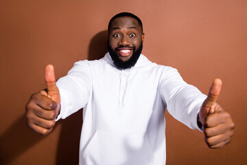 Photo of funny pretty guy dressed white sweatshirt showing two thumbs up isolated brown color background