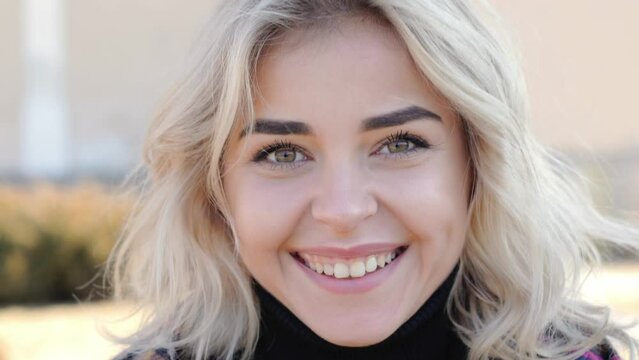 close up portrait of beautiful blonde young woman looking up to the camera and smiling charmingly. Close up of lady face, girl opening her beautiful eyes