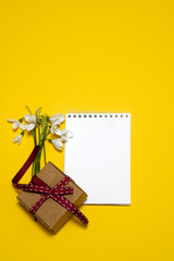 sheet for writing, snowdrops, gift box on a yellow background. card, congratulations on March 8. place for text