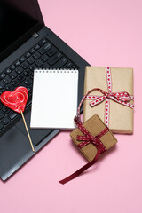 laptop, red heart-shaped lollipop, gift boxes tied with ribbon, notepad