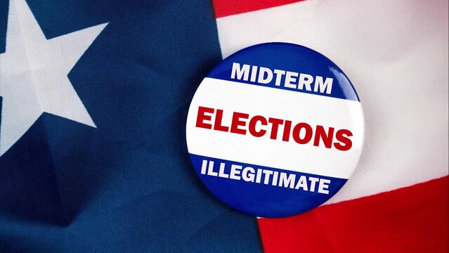 midterm elections illegitimate text quote on election button laying on the star spangled banner. united states of america concept.