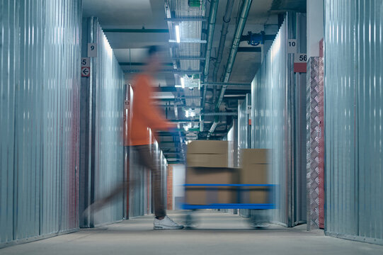 Worker transporting goods on the warehouse trolley