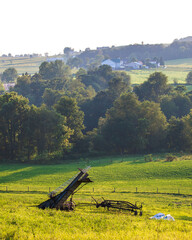 Farm Equipment Sitting in an Open Green Field with Trees in the Background