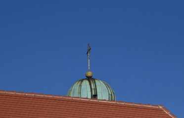 Fototapeta na wymiar Turmspitze der Maria-Hilf-Kirche hinter einem Hausdach