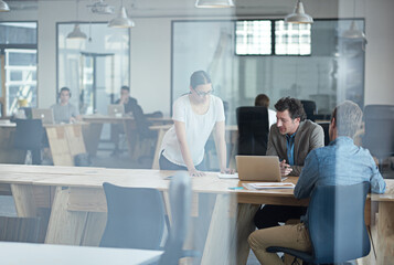 Obraz premium Sharing their creative ideas. Through the glass shot of a group of colleagues working together in an office.