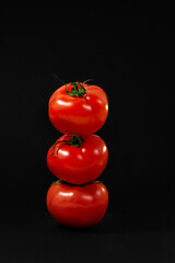 three tomatoes on a black background