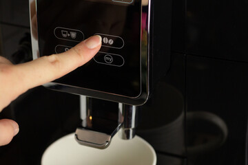 Closeup of a person pushing a button on a coffee machine. 