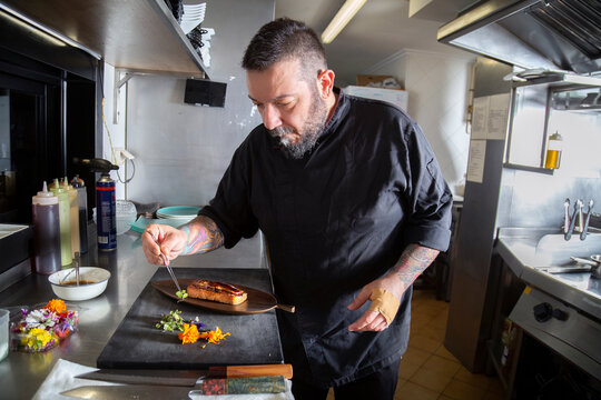 Chef taking microgreen while cooking in kitchen