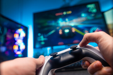 The gamer holds a gamepad in his hands. Video games on big screen TV. Teenagers play adventure video games. Win prizes. Youth culture, virtual reality, modern technologies, communications, leisure. - 487408095