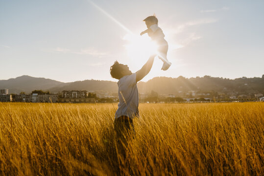 Anonymous man spending time with little son in yellow field