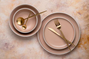 Collection of round beige plates of different sizes on the table, top view. Golden cutlery and...