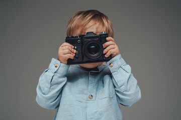 Little kid photographer with photocamera isolated on gray - obrazy, fototapety, plakaty