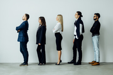 Long line of diverse professional business people standing in a queue in profile isolated on white background