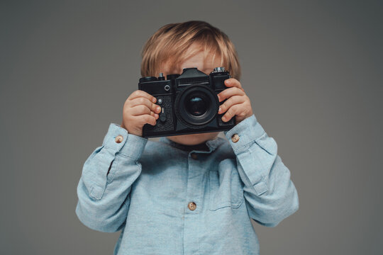 Little kid photographer with photocamera isolated on gray
