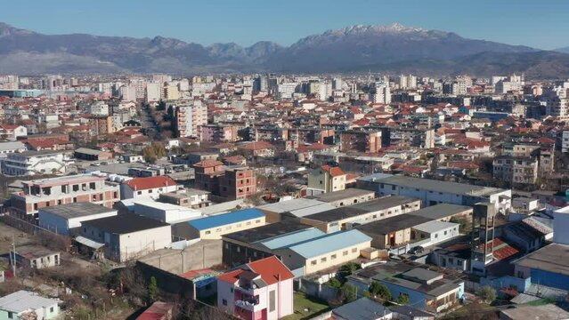 Shkoder Albania cityscape - skyline of a city, with buildings and houses, surrounded by high hills and mountains. Aerial drone view of Shkodra (Skadar) on a sunny day with clear blue sky.
