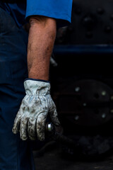 Man's Arm with a Blue Short Sleeve and Dirty White Glove Holding a Lever